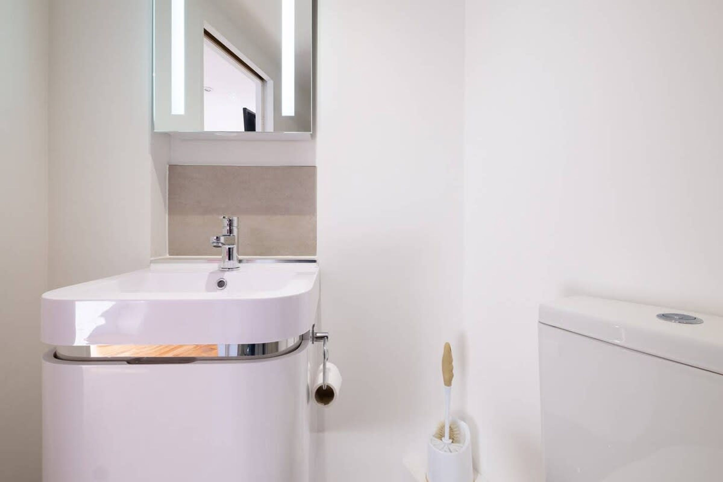 Une salle de bain avec un lavabo blanc, un miroir au-dessus et des toilettes.