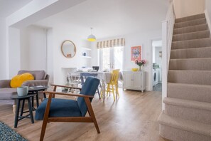 A modern living room with a blue chair, a dining area, and a staircase. - Host Stay Millfield House (Brighton)