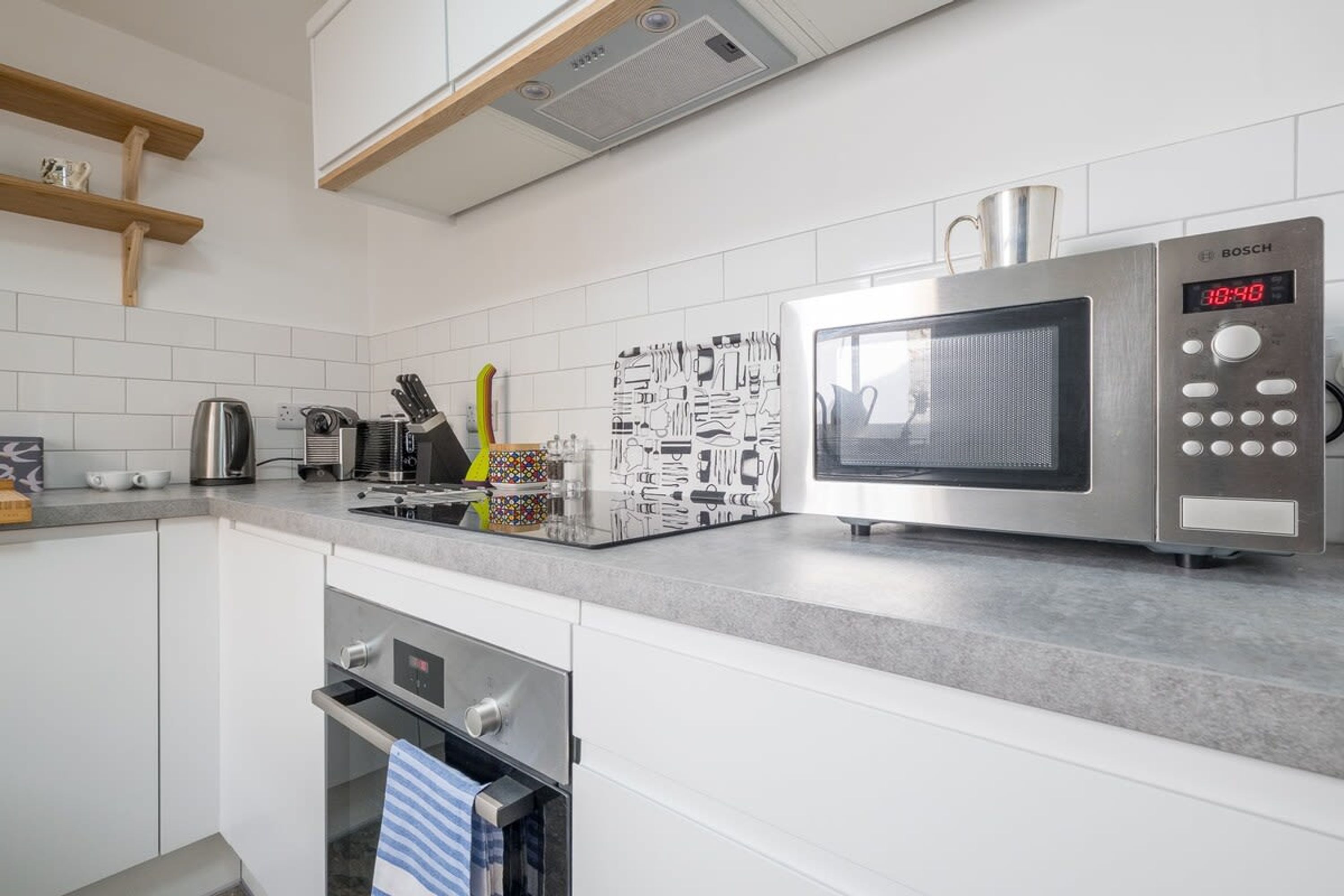 A modern kitchen with white cabinets, a Bosch microwave, and a kettle.