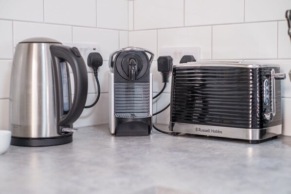 A kitchen with a kettle, a coffee maker, and a toaster on the counter. - Host Stay Millfield House (Brighton)