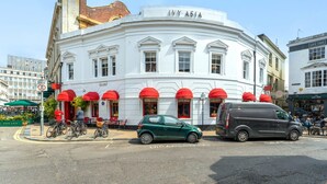 A white building with red awnings and the name "Ivy Asia" on the facade. - Host Stay Over Arches (Brighton)