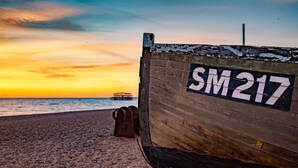 A wooden boat with the number SM217 on a pebbled beach at sunset. - Host Stay Seven Dials Apartment (Brighton)