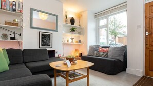 Ein Wohnzimmer mit einer Couch, einem Couchtisch, Regalen mit Büchern und Dekoration sowie einem Fenster mit Blick.