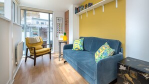 A modern living room with a blue sofa, yellow armchair, and a wooden coffee table. - Host Stay Kingscote Townhouse (Brighton)