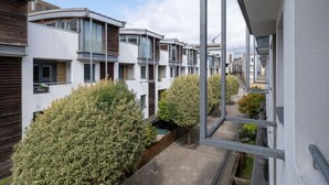 A row of modern townhouses with balconies, a clear sky, and a narrow pathway between them. - Host Stay Kingscote Townhouse (Brighton)