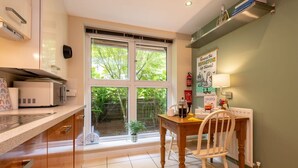 A modern kitchen with a dining area, large windows, and a view of greenery outside. - Host Stay Kingscote Townhouse (Brighton)