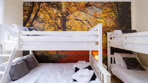 A bunk bed room with a large autumn tree mural on the wall.