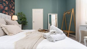 A neatly made bed with white linens and a beige throw blanket, a wooden dressing table with a mirror, a white dresser, and a wooden wardrobe. - Host Stay Round Hill Apartment (Brighton)