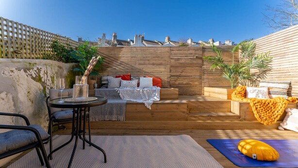 A cozy outdoor patio with a wooden bench, a small round table, and a yoga mat. - Host Stay Round Hill Apartment (Brighton)