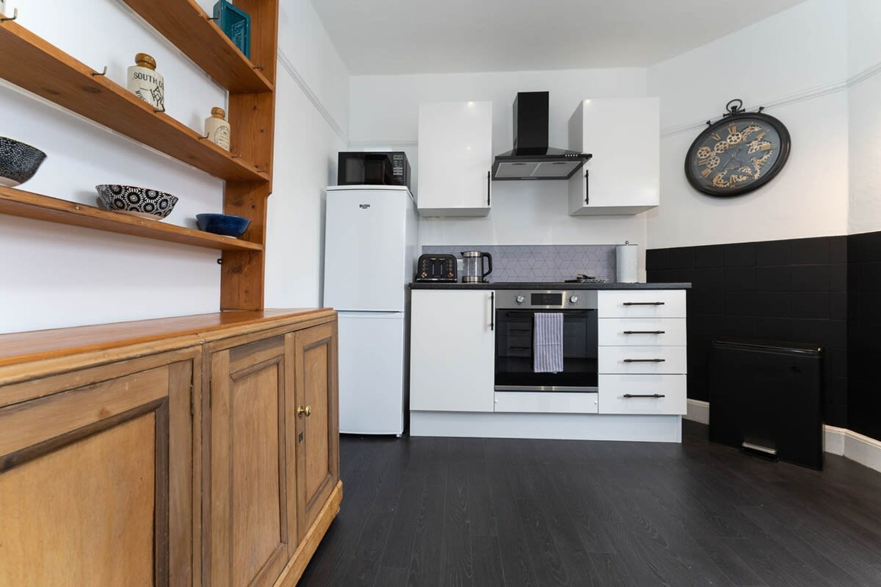 A compact kitchen with white cabinets, a microwave, a coffee maker, and a black oven.