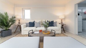 A modern living room with a white sofa, two side tables with lamps, a coffee table, and a potted plant. - Host Stay Sea View on Manchester Road (Brighton)