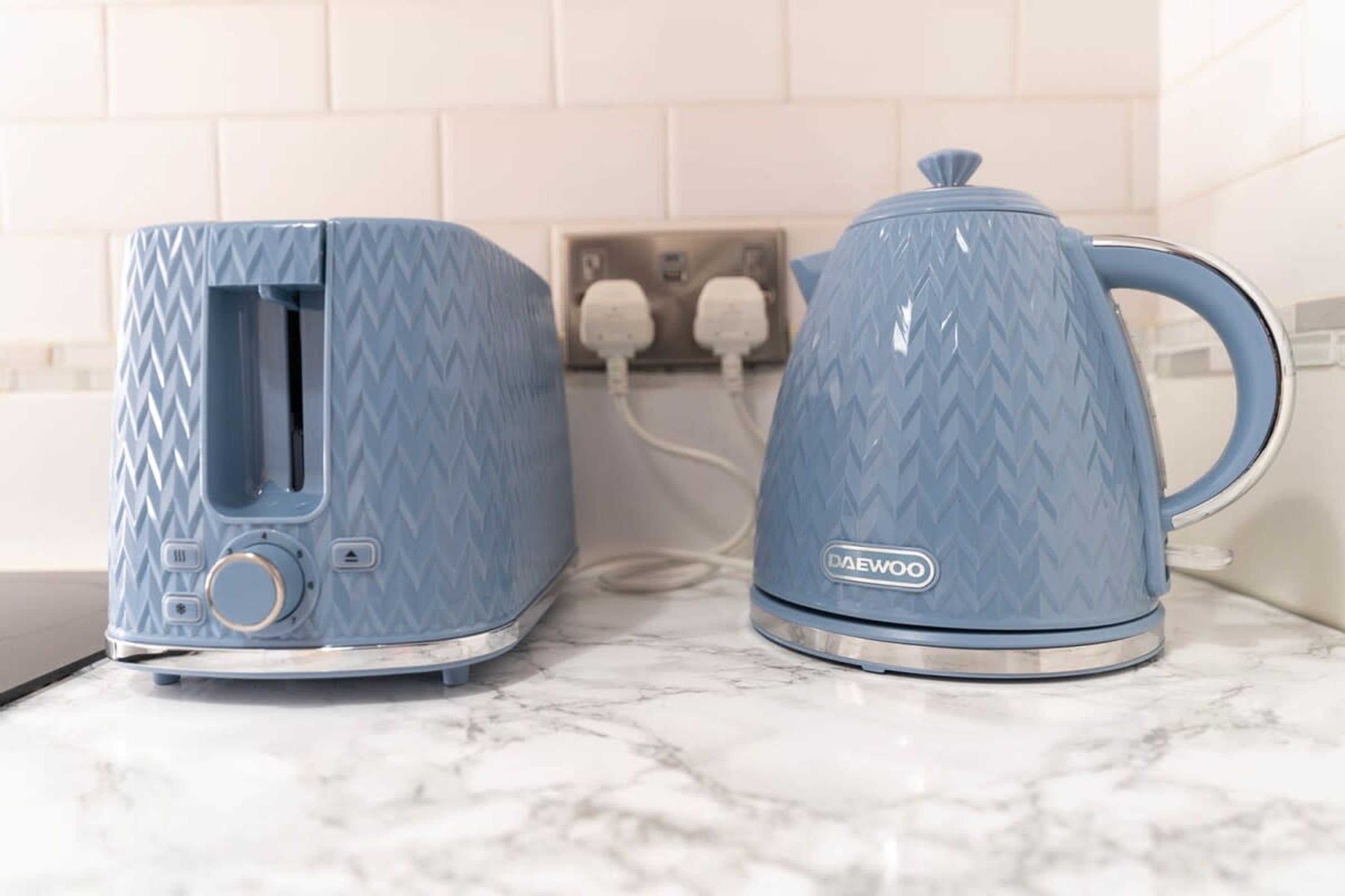 A kitchen with a toaster and a kettle on a marble countertop.