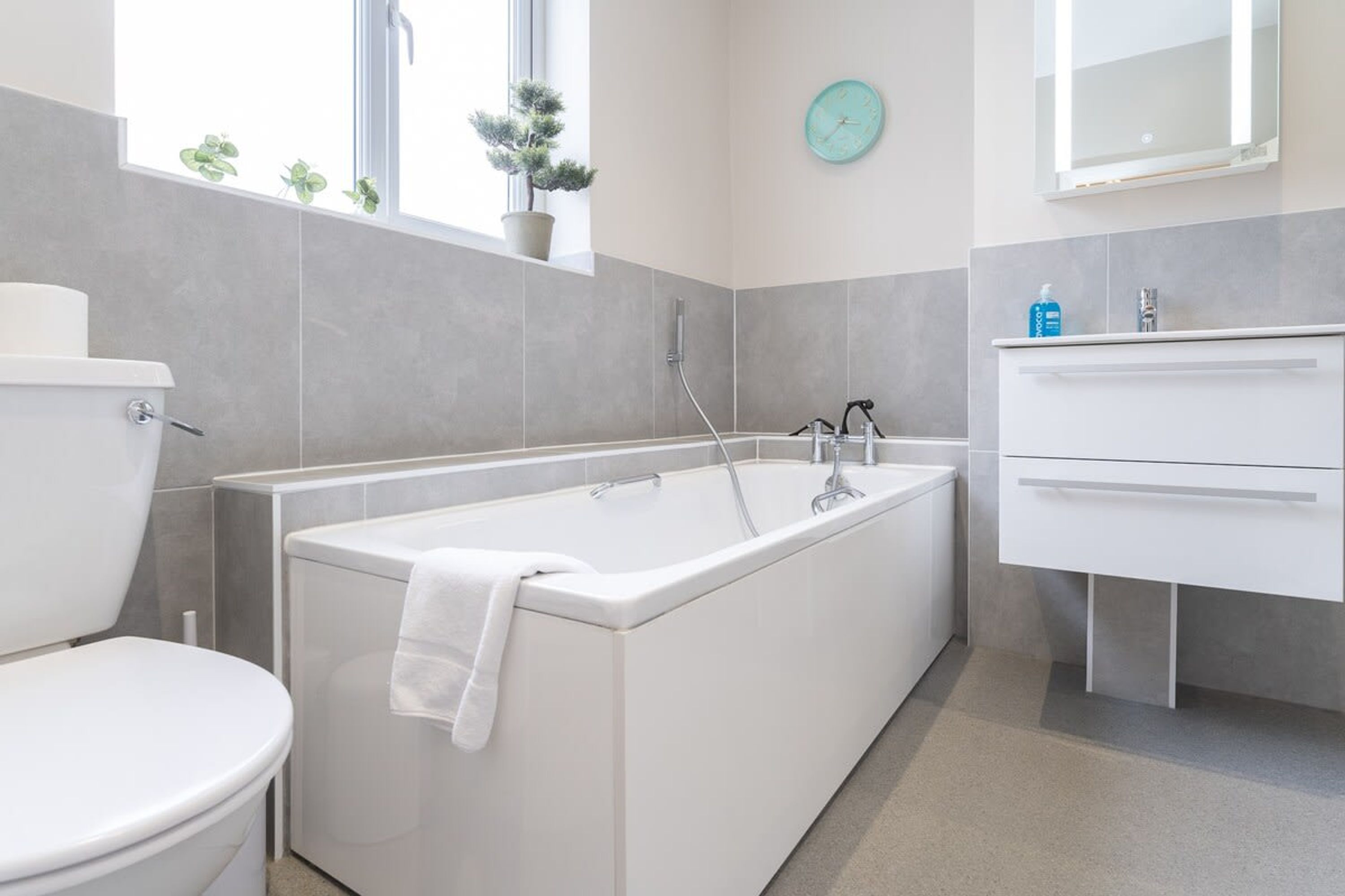 A modern bathroom with a bathtub, toilet, and a sink with a mirror.