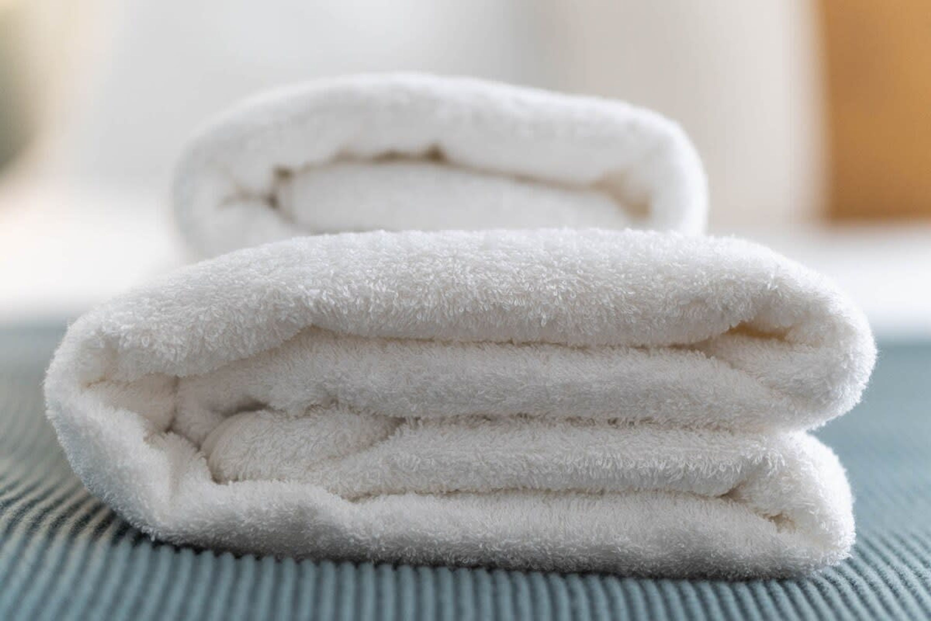 A stack of white towels on a textured surface.