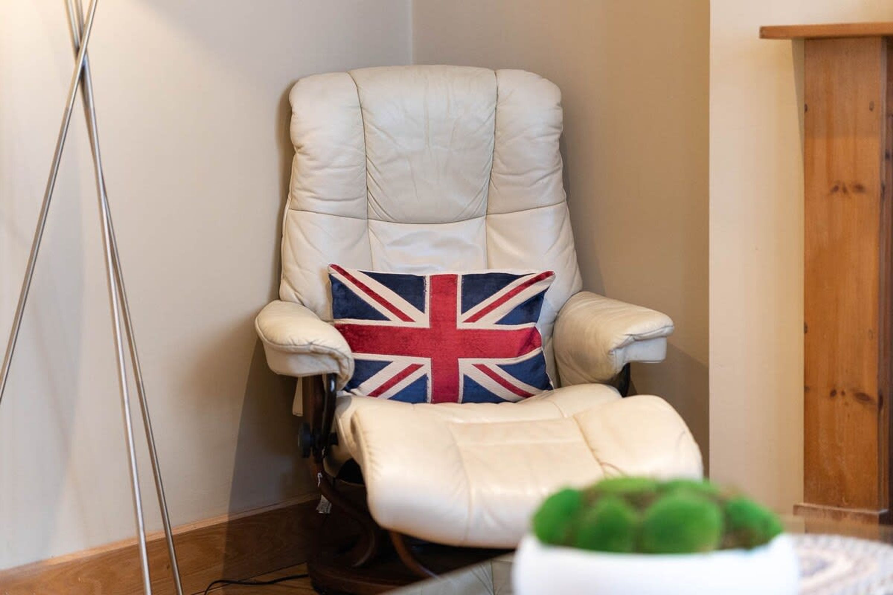 Un angolo di una stanza con una poltrona in pelle bianca e un cuscino con la Union Jack.