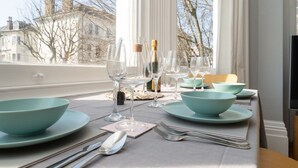A dining table set with teal bowls, wine glasses, and cutlery, overlooking a building with bare trees. - Host Stay Alexandra Villas (Brighton)