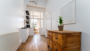 A hallway with wooden flooring, white walls, a wooden dresser with a plant, and a framed artwork. - Host Stay Alexandra Villas (Brighton)