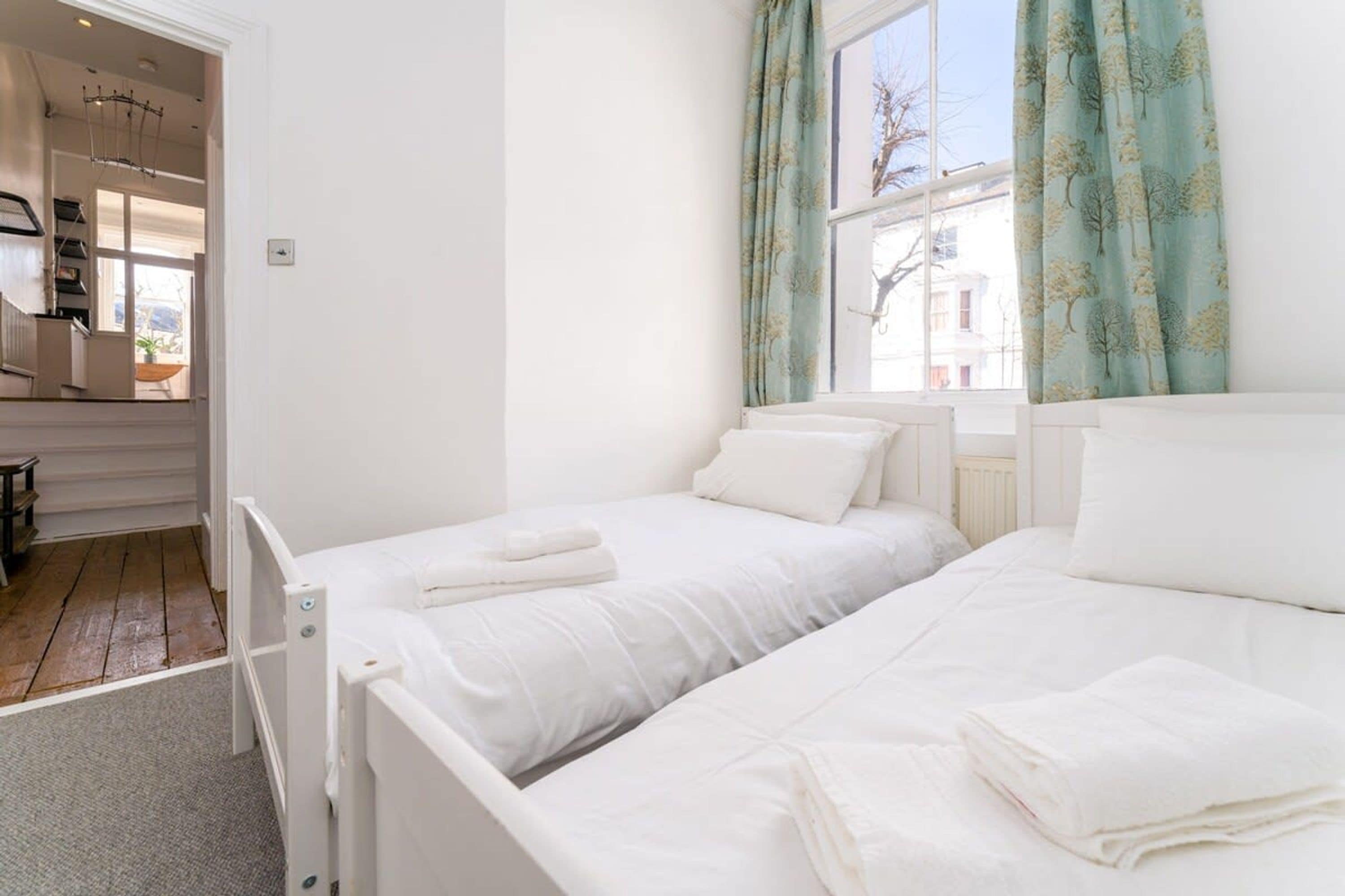 Un dormitorio con dos camas, una ventana con cortinas y vistas al exterior.