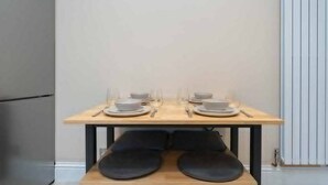 Una mesa de comedor dispuesta con platos, fuentes y cubiertos, con cojines negros debajo.