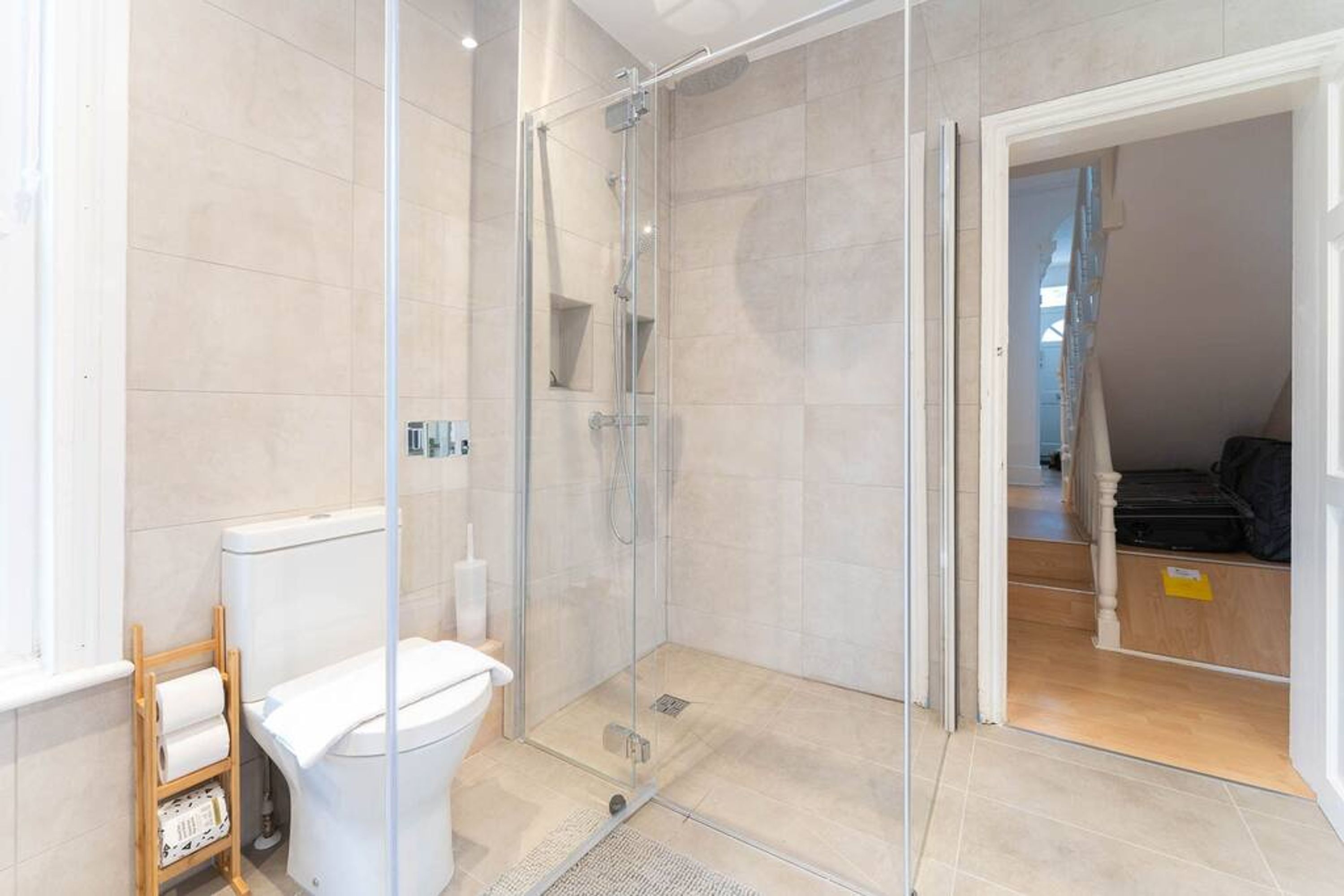 Ein modernes Badezimmer mit Duschkabine aus Glas, Toilette und Ablagefach mit Pflegeprodukten.
