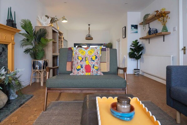 A cozy living room with a green sofa, a patterned throw pillow, and a coffee table with a blue bowl.