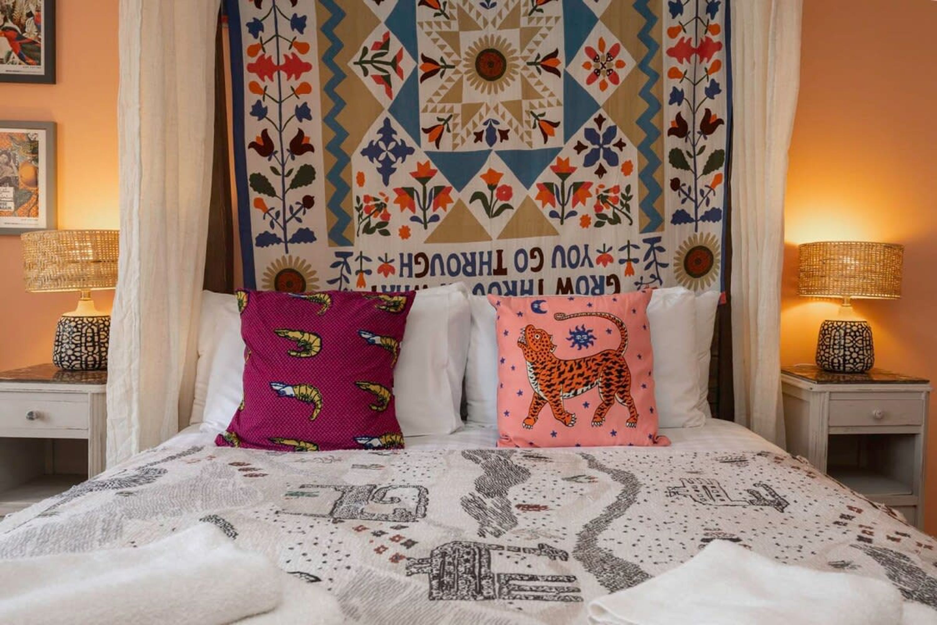 A bed with patterned bedding, two pillows with animal prints, and a tapestry with geometric and floral designs.
