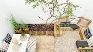 A wooden deck with a white table and chairs, surrounded by potted plants and a small tree. - Host Stay The Charles Street Retreat (Brighton)