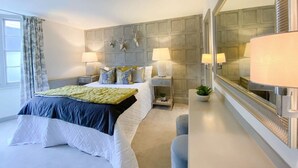 A modern bedroom with a large bed, two bedside tables with lamps, a mirror, and a decorative wall panel. - Host Stay The Charles Street Retreat (Brighton)