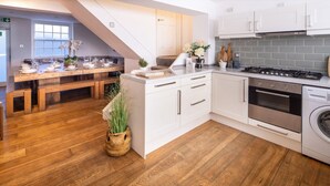 A modern kitchen with white cabinetry, a wooden dining table, and a built-in stove. - Host Stay The Charles Street Retreat (Brighton)