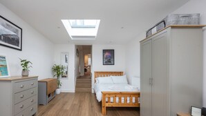 Une chambre avec un puits de lumière, un lit, une armoire, un bureau et une chaise.