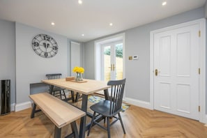 A dining area with a wooden table, black chairs, a bench, a clock, and a window with a view. - Host Stay Brighton Laines House (Brighton)