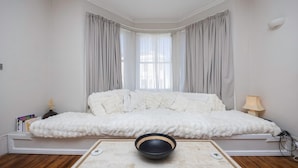 Ein Zimmer mit einem weißen Sofa, einer schwarzen Schale auf einem Teppich und einer Lampe auf einem Beistelltisch.