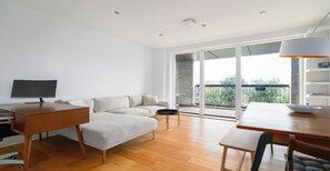 Ein modernes Wohnzimmer mit Sofa, Esstisch, Fernseher und einem Balkon mit Blick.