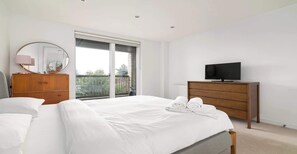 Ein Schlafzimmer mit Bett, einem Holzschrank, einem Fernseher und einem Balkon mit Blick.