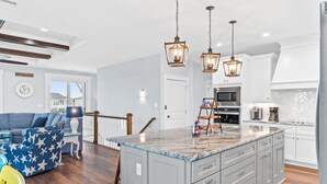 Una cocina moderna con una isla central, armarios blancos e iluminación colgante.