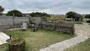 A patio area with two Adirondack chairs, a stone wall, and a paved path leading to a car. - Kerdraffic Pointe de la Torche (Plomeur)