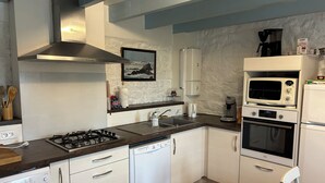 A compact kitchen with white cabinets, a gas stove, a dishwasher, a microwave, and an oven. - Kerdraffic Pointe de la Torche (Plomeur)