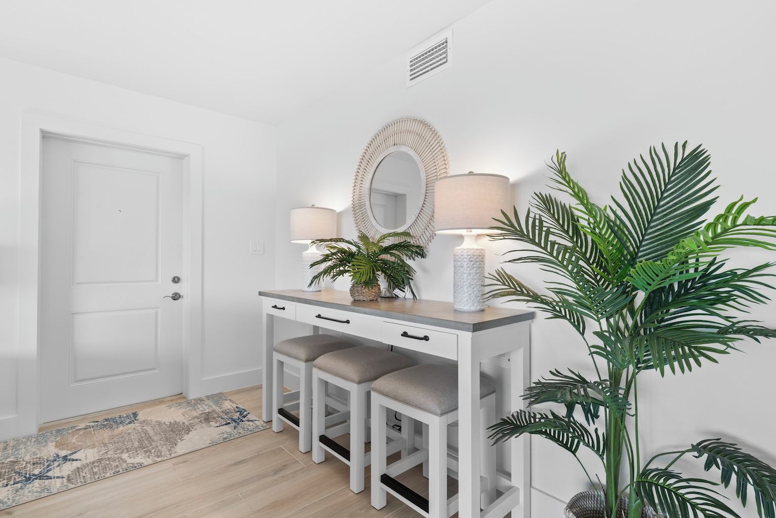 A white vanity with a mirror, two lamps, and a potted plant.