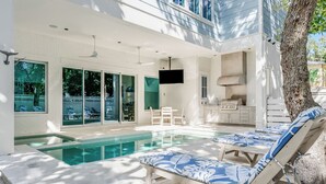 A modern outdoor pool area with lounge chairs, a barbecue, and a dining area. - Mischievous Mermaid|Easy Beach Access|Private Pool|Game Room|Golf Cart (Seagrove Beach)