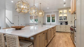 A spacious kitchen with a large island, wooden cabinets, and pendant lights.