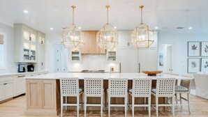 A modern kitchen with a central island, white cabinetry, and pendant lighting.