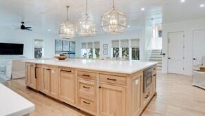 A spacious kitchen with a large island, wooden cabinets, and pendant lighting.