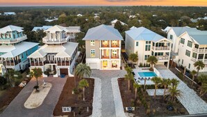 A large, multi-story residential building with a central courtyard, a swimming pool, and a view of the surrounding landscape.