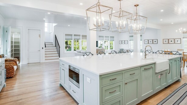 A spacious kitchen with a large island, modern pendant lights, and a view of the outdoors.