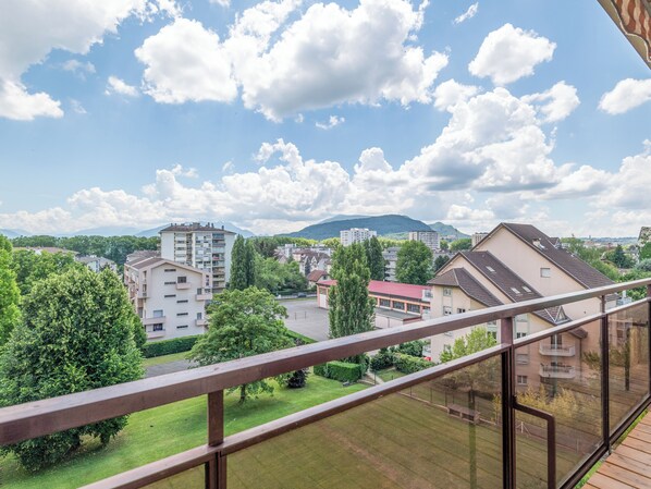 A residential area with a mix of apartment buildings, a green park, and a mountain in the background.