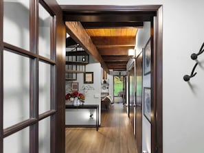 A hallway with wooden flooring, a staircase, and a dining area with a table and chairs.
