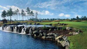 Un parcours de golf agrémenté d’une cascade, d’arbres et d’un petit bâtiment.