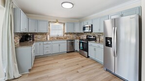 Eine moderne Küche mit hellblauen Schränken, einem Edelstahl-Kühlschrank, einer Mikrowelle und einem eingebauten Backofen.