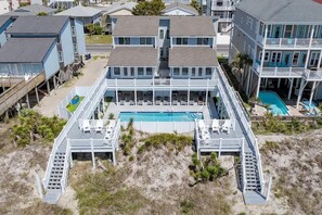 A beachfront property with a central pool, multiple decks, and a beach access walkway.