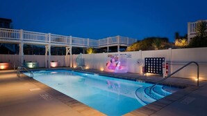 En swimmingpool med ett vitt poolområde, en livräddarstation och en avslappningshörna vid poolkanten.